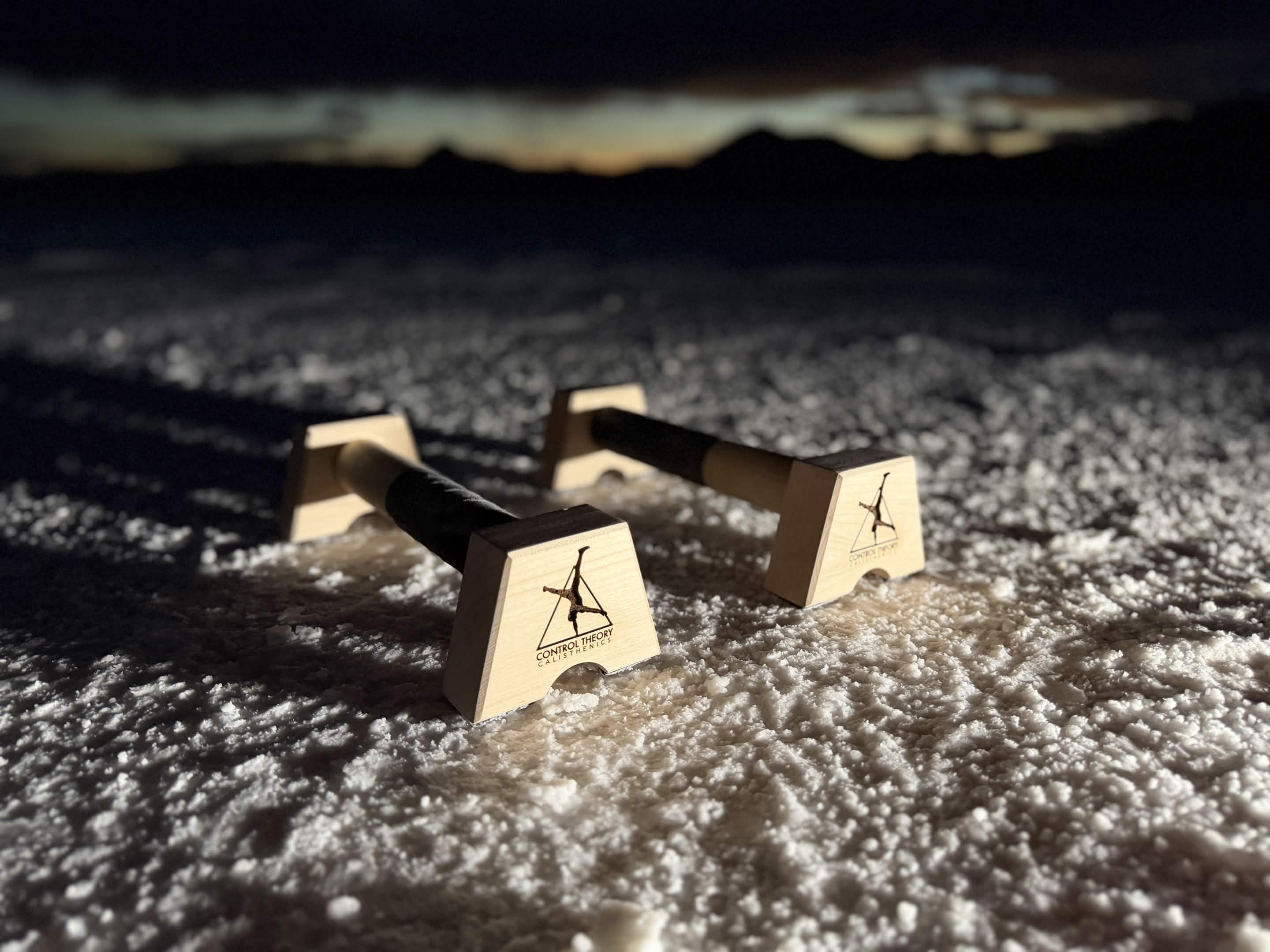 Close view of both Control Theory parallettes showing the maple frame, taped grip and branded side panel